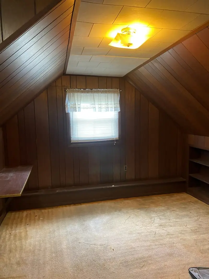 Attic bedroom with wood-paneled walls and old carpet, Valley Stream, NY