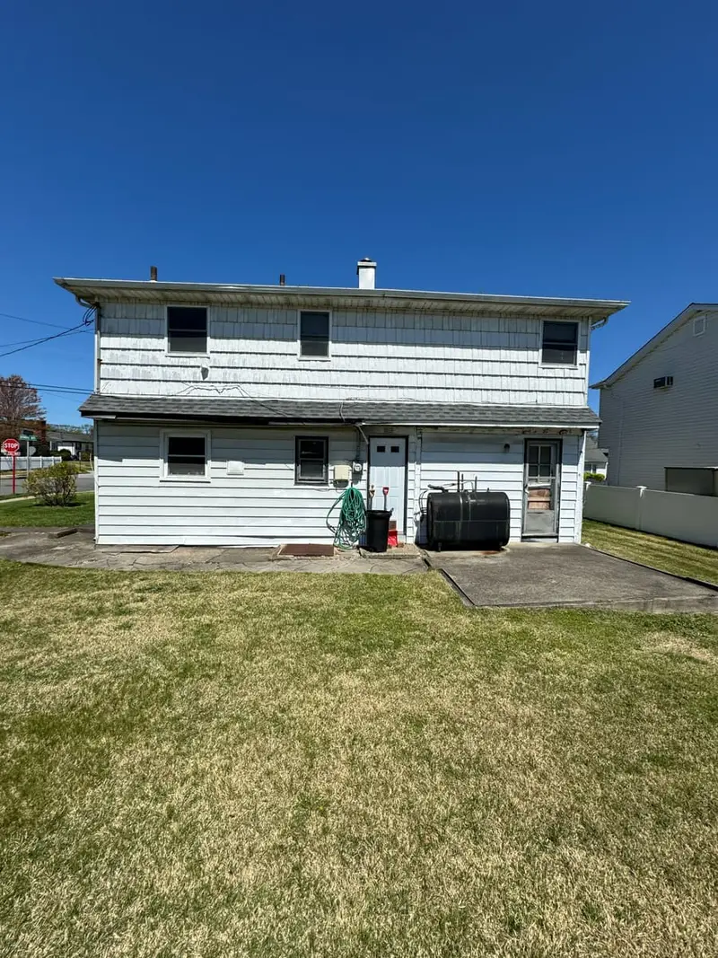 Back of a two-story house over a wide lawn, Valley Stream, NY