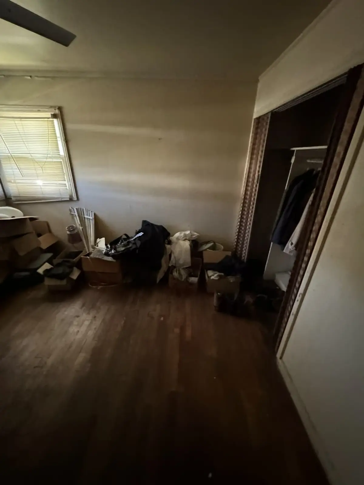 Selling a hoarder house in Valley Stream: empty bedroom with boxes left on a bare wood floor