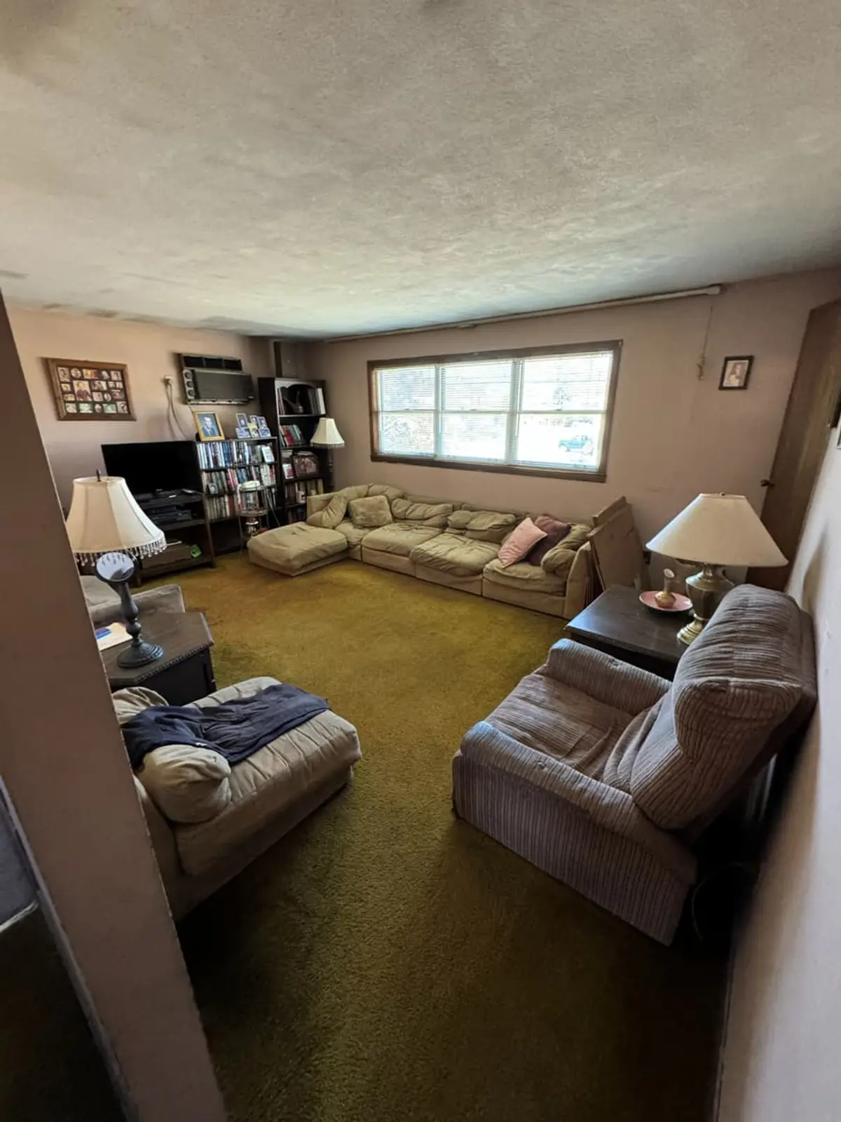Selling a house during a divorce in Valley Stream: living room with olive carpet and worn sofas
