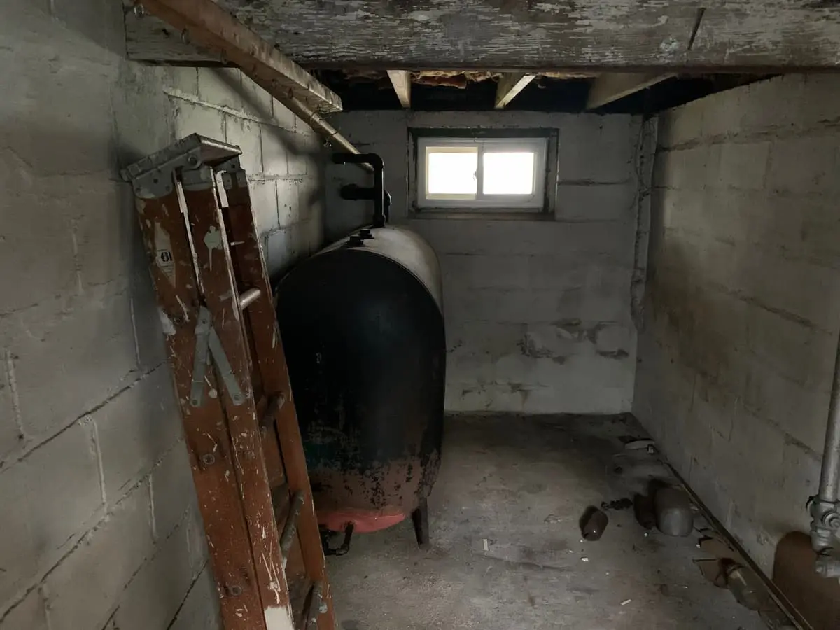 Selling a house with an oil tank in Valley Stream: old oil tank in a dark cinder-block basement