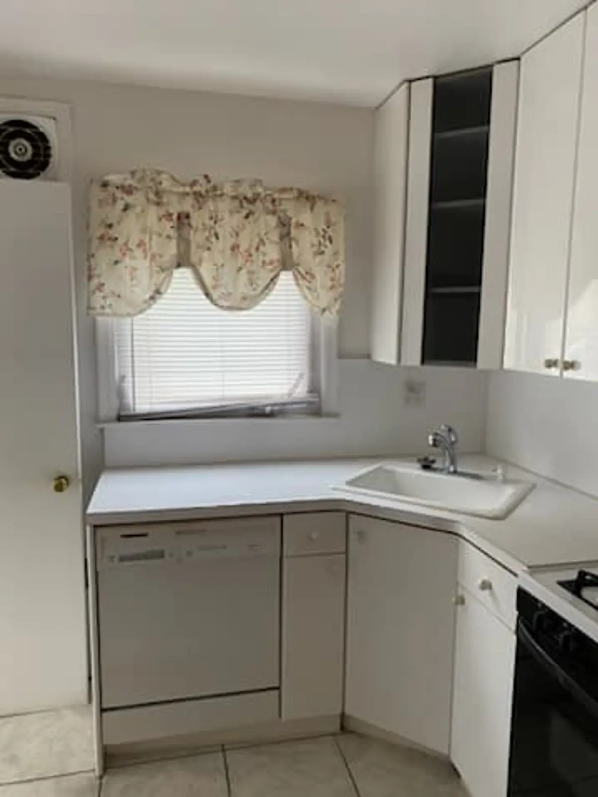 Selling a house after a life change in Valley Stream: small white kitchen with a corner sink