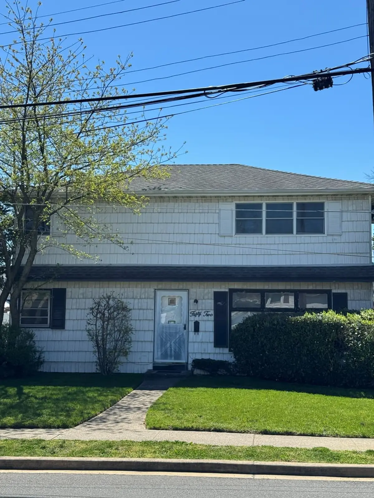 Two-family house with white siding and a small front lawn, Valley Stream, NY